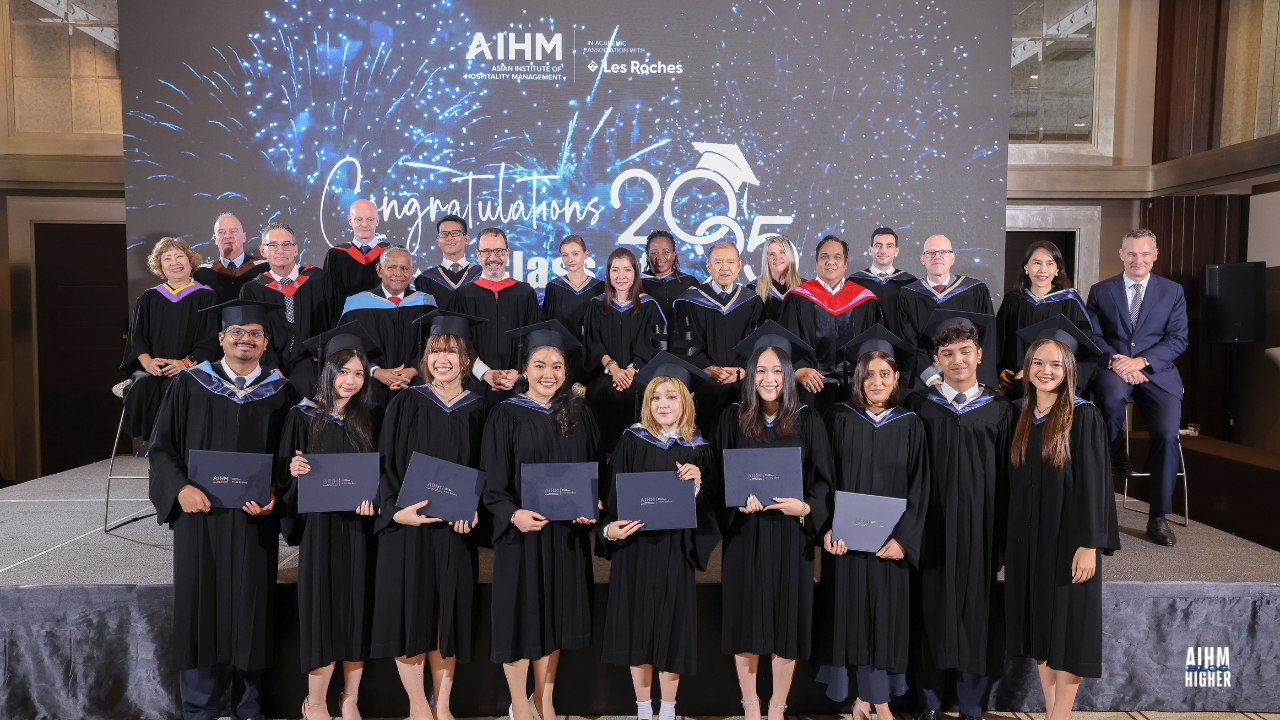 AIHM BBA3 graduates stand in front of the faculty and management team, smiling and holding their certificates during the Graduation Ceremony 2025. The celebratory backdrop reads “Congratulations Class of 2025.”